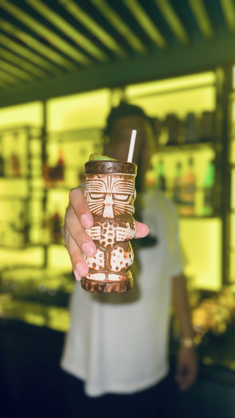 Signature carved tiki mug cocktail glowing against the back bar at Mai Tai Beach Bar Boracay