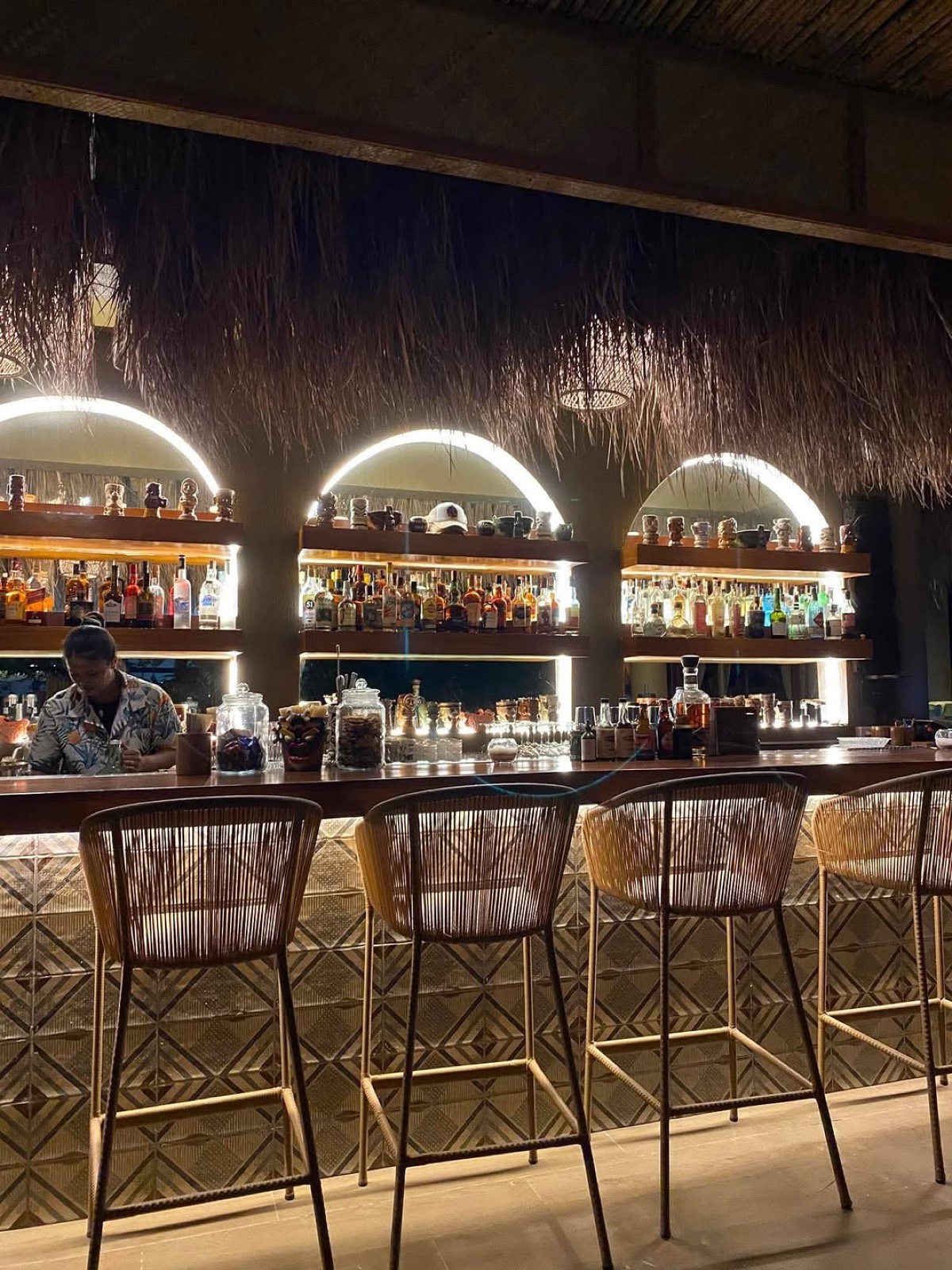 Warmly lit arched back bar and rattan stools at Mai Tai Beach Bar Siquijor